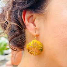 Load image into Gallery viewer, A close-up image of a person wearing a gold-colored hoop earring with a floral pattern on the hoop.