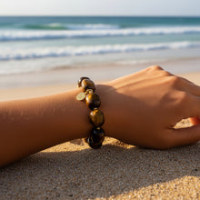 Load image into Gallery viewer, A beaded stretch bracelet made of polished tiger's eye beads in shades of brown, yellow, and black, separated by small gold spacers and finished with a gold clasp.